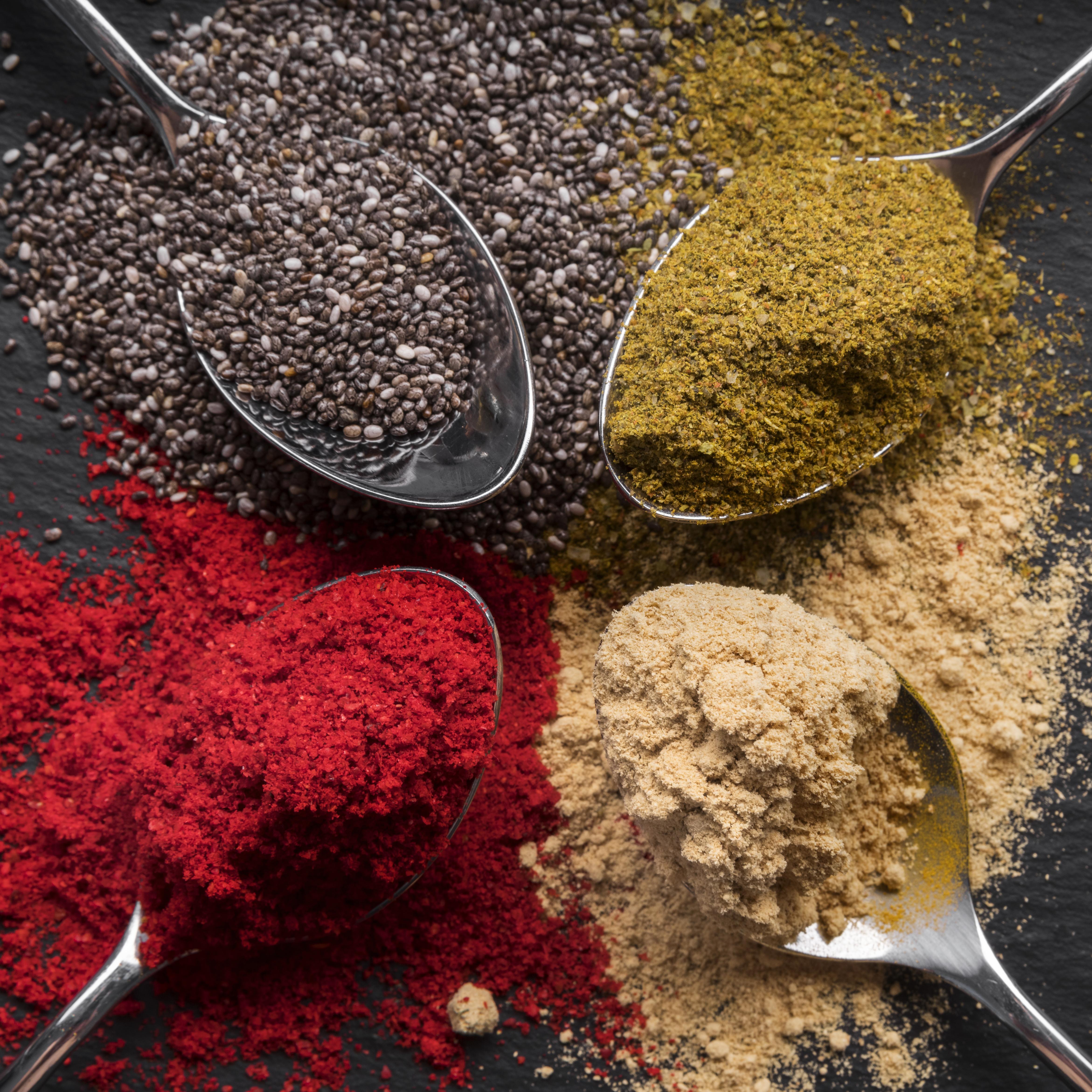Flat lay colorful spices on black background - premium spice arrangement